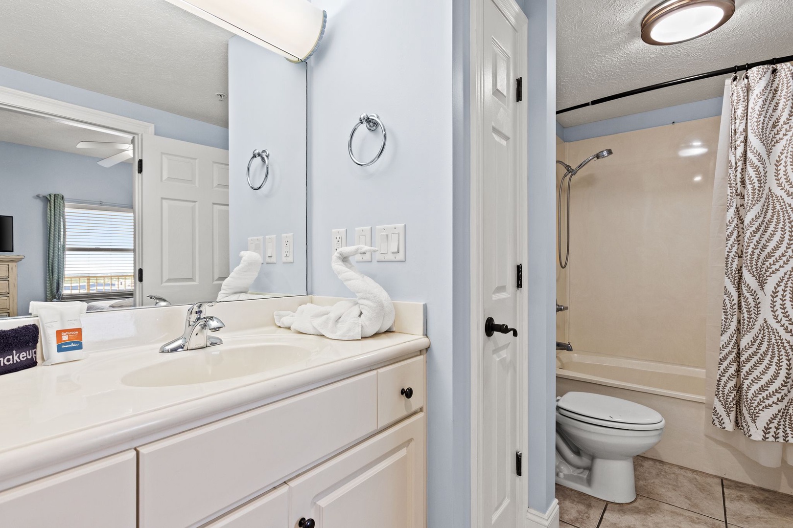 Your bathroom features a bright vanity with crisp white cabinetry and fresh towels, plus a separate shower-tub combo for refreshing mornings and relaxing evenings.