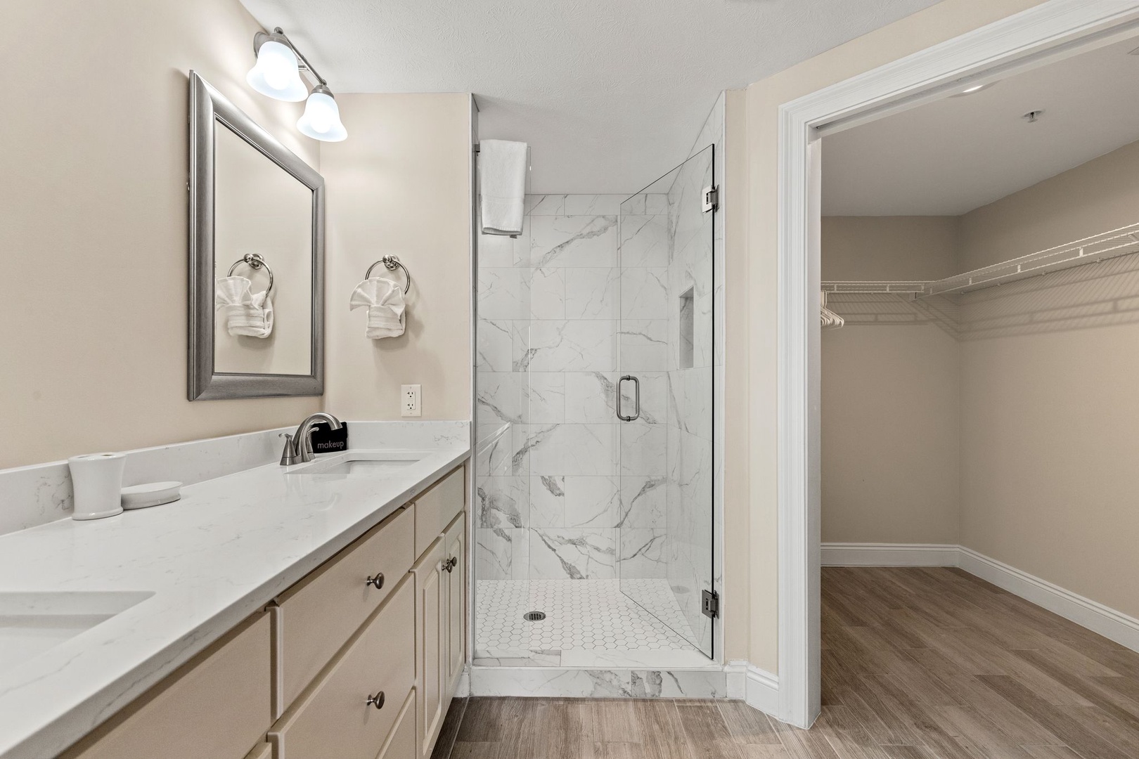 Step into your elegant marble-tiled shower featuring a spacious glass enclosure, perfect for refreshing morning routines in this beautifully appointed bathroom.
