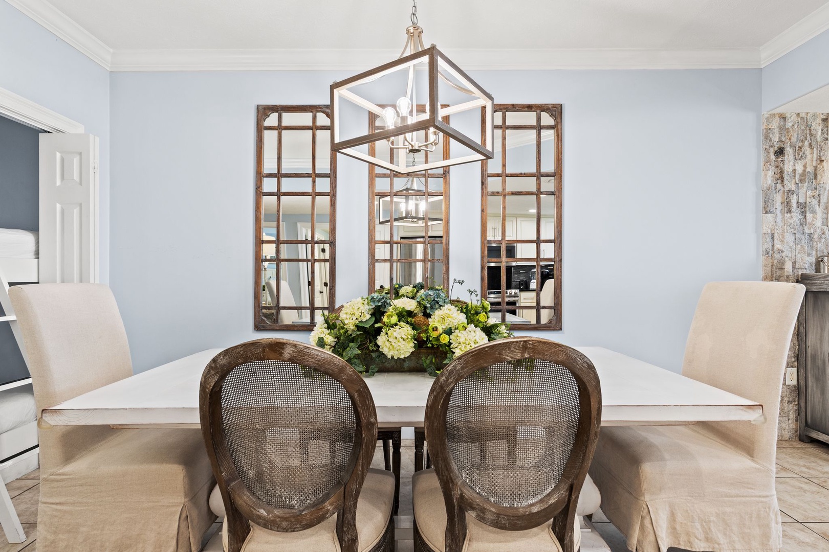 Picture yourself gathering around this elegant table for morning coffee or evening meals. Soft lighting from the statement chandelier creates a welcoming ambiance, while fresh blooms and thoughtful décor make every moment feel special.