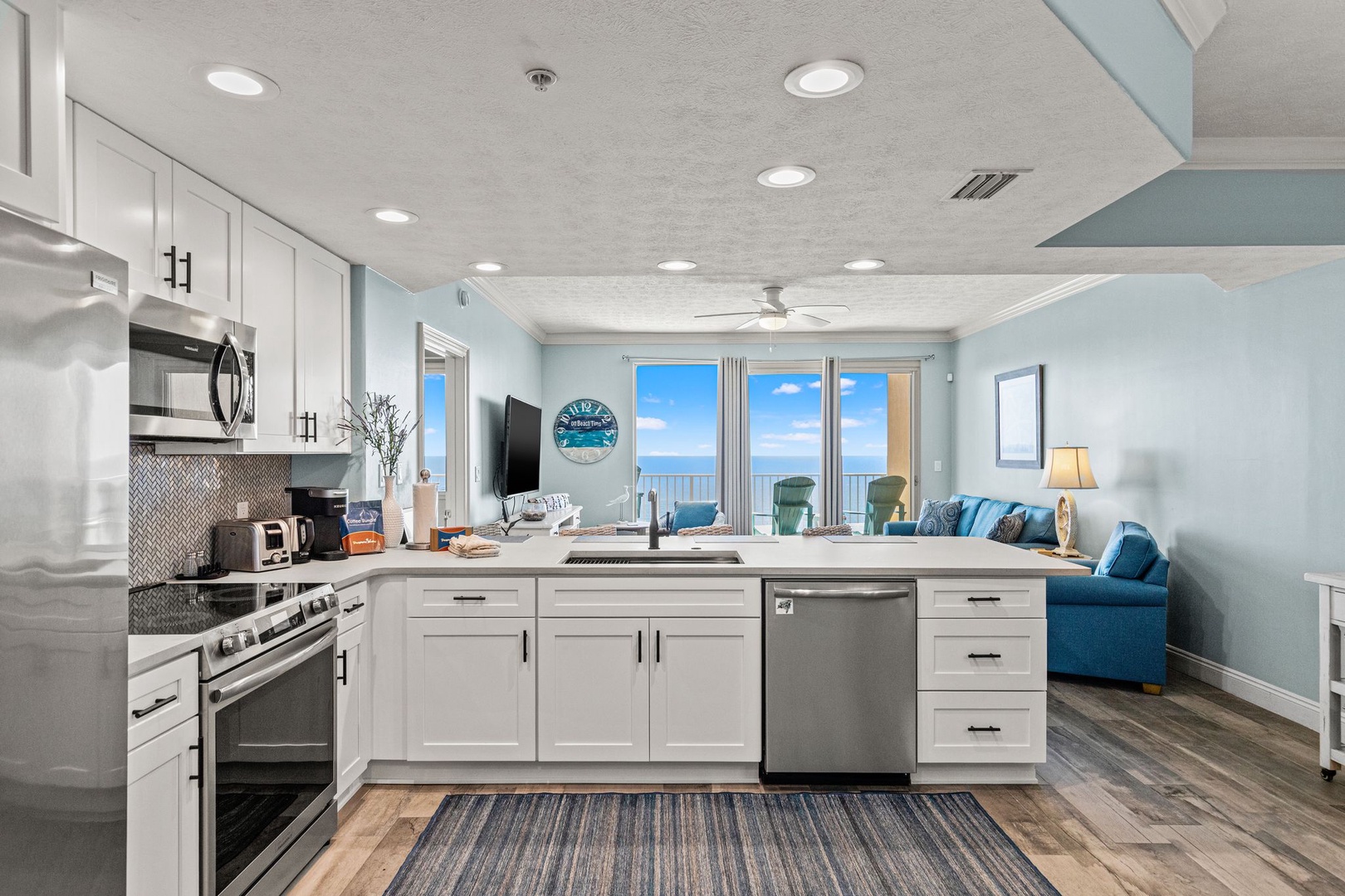 Picture yourself cooking meals in this bright, open kitchen while gazing at stunning ocean views. White cabinetry and modern appliances create a clean, coastal feel that's perfect for your beach getaway.