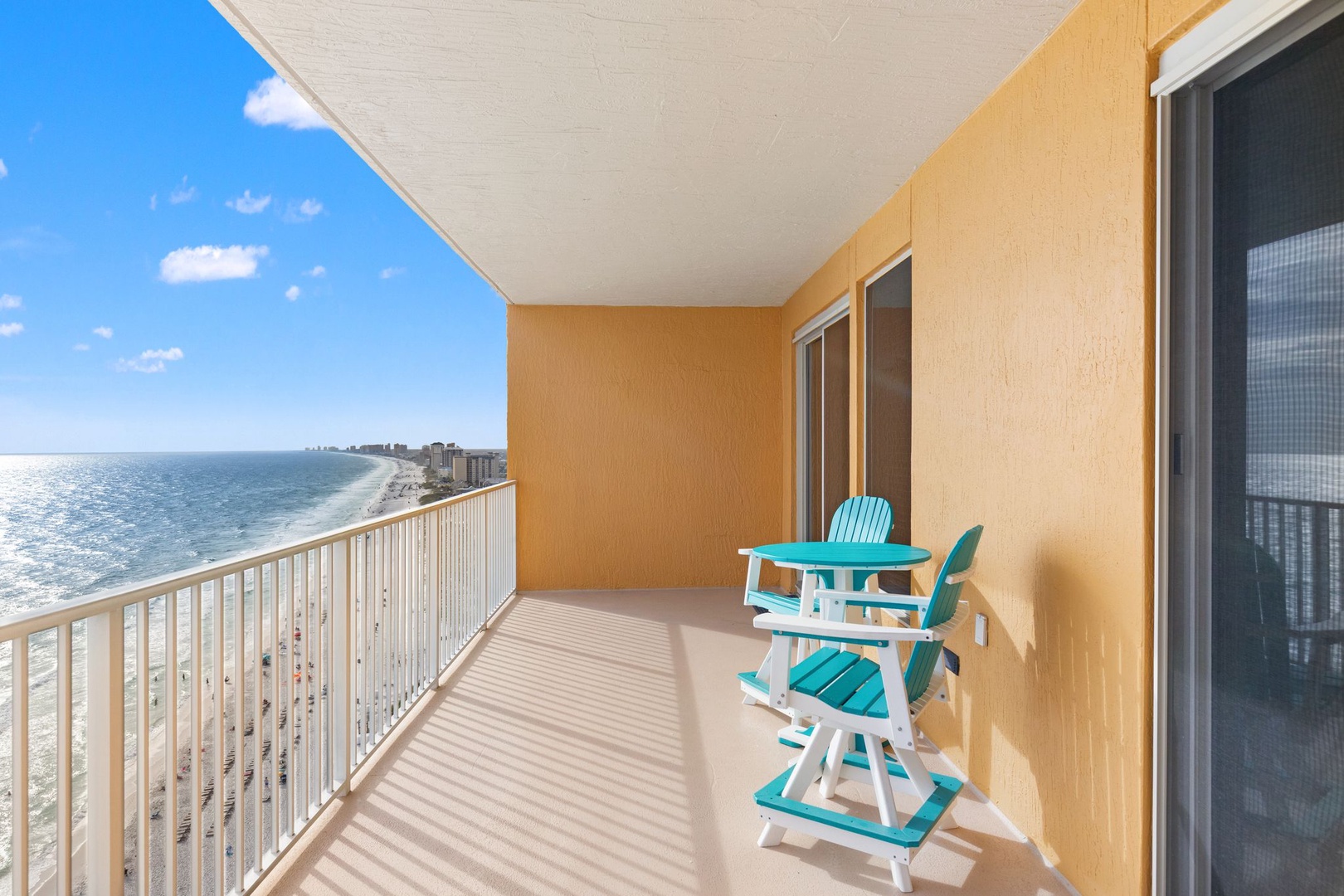 Spacious private balcony with sweeping coastal views, featuring bright beach chairs perfect for morning coffee or sunset watching over the ocean.