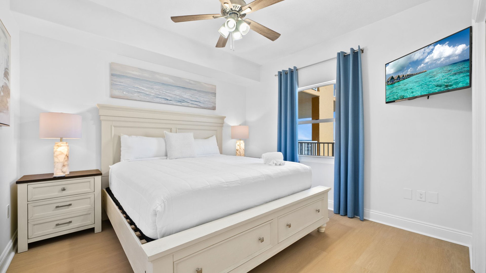 Unwind in your serene bedroom featuring crisp white linens, coastal artwork, and soft lighting for peaceful nights.