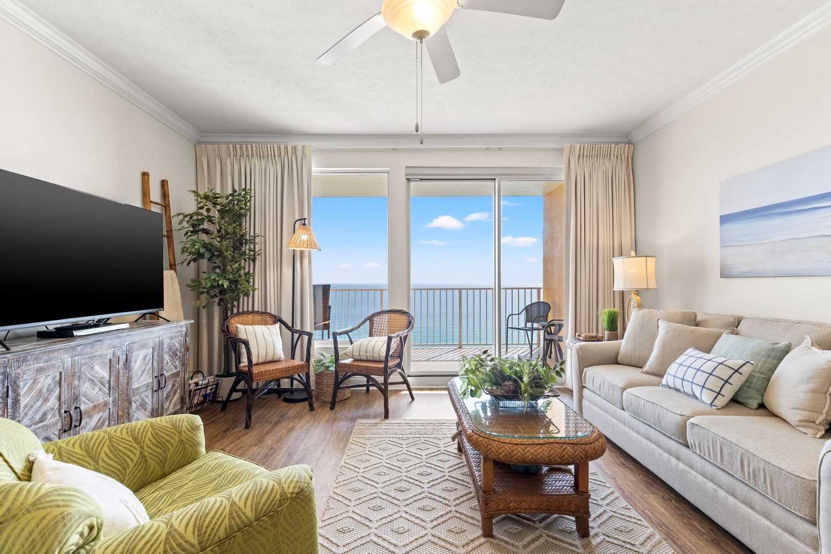 Sink into plush seating as you gaze through floor-to-ceiling glass doors framing endless ocean views. Your private balcony awaits with gentle sea breezes and coastal calm.