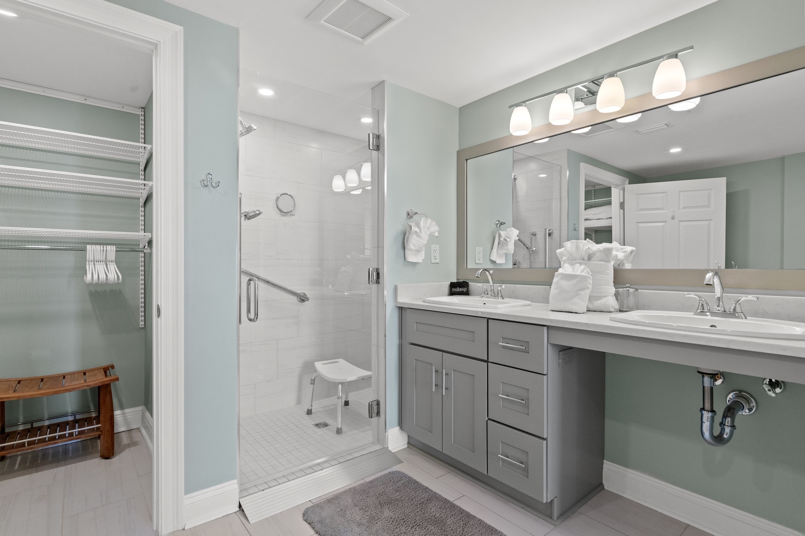 Unwind in your spa-like bathroom featuring soothing mint walls, elegant dual vanities, and a spacious glass shower with modern fixtures.