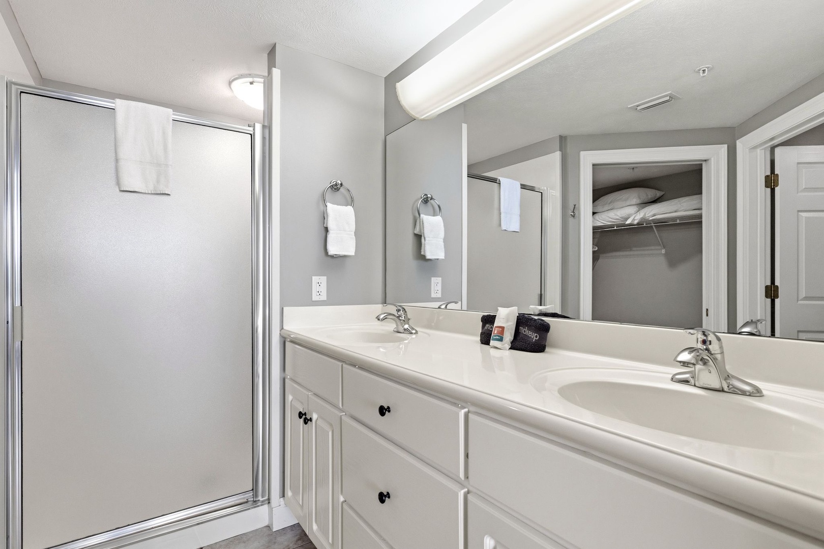 Refresh in your spacious bathroom featuring dual sinks, ample counter space, and a glass-enclosed shower for your comfort.