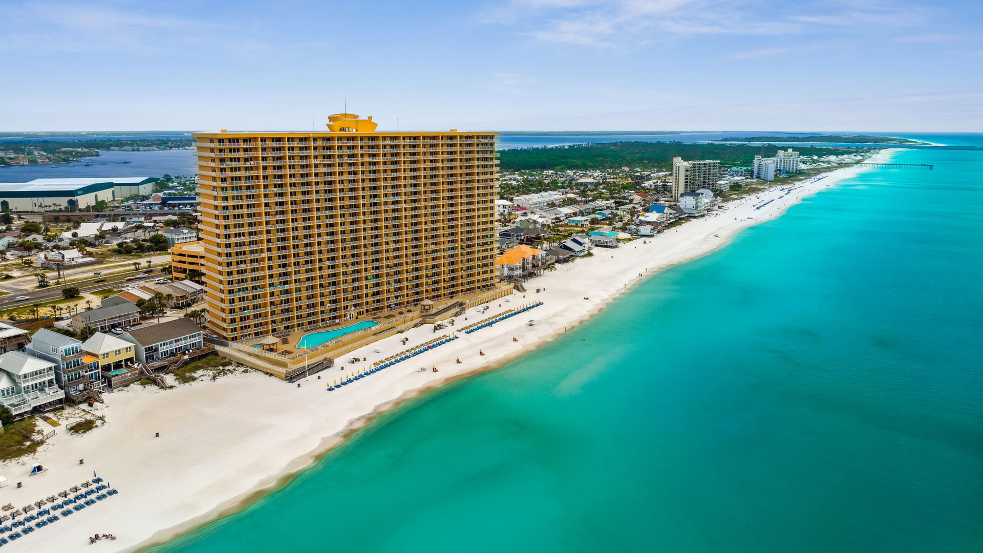 Stunning beachfront property sits directly on pristine white sand beach with crystal-clear turquoise waters stretching endlessly along the coastline.