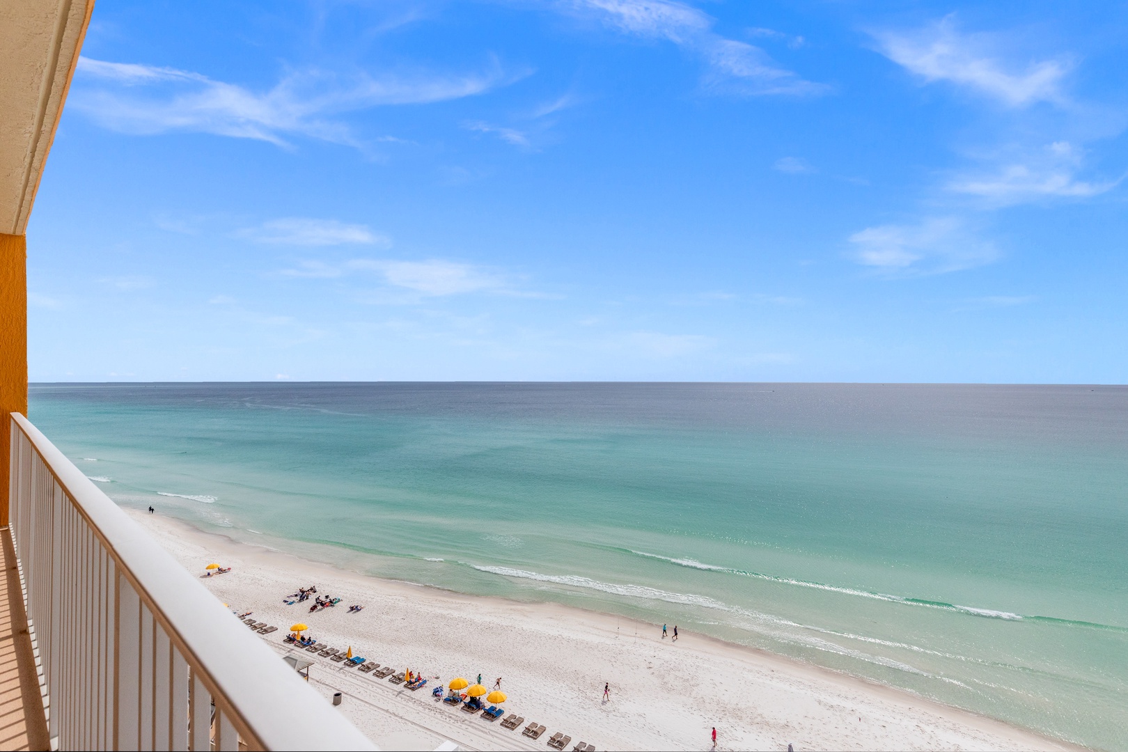 Stunning beachfront view from property balcony showcasing pristine white sand beach and crystal-clear turquoise waters.