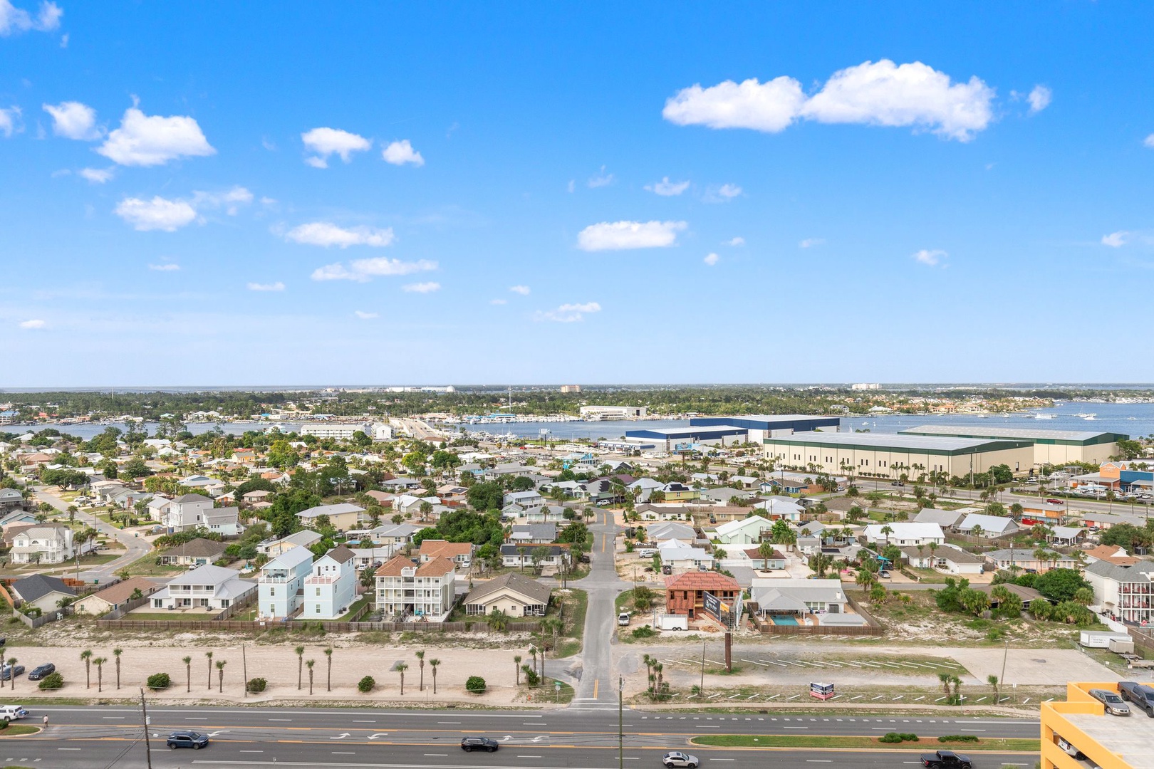 Aerial view of a coastal neighborhood with residential homes, palm-lined streets, and waterfront access, offering a peaceful community setting near the bay.