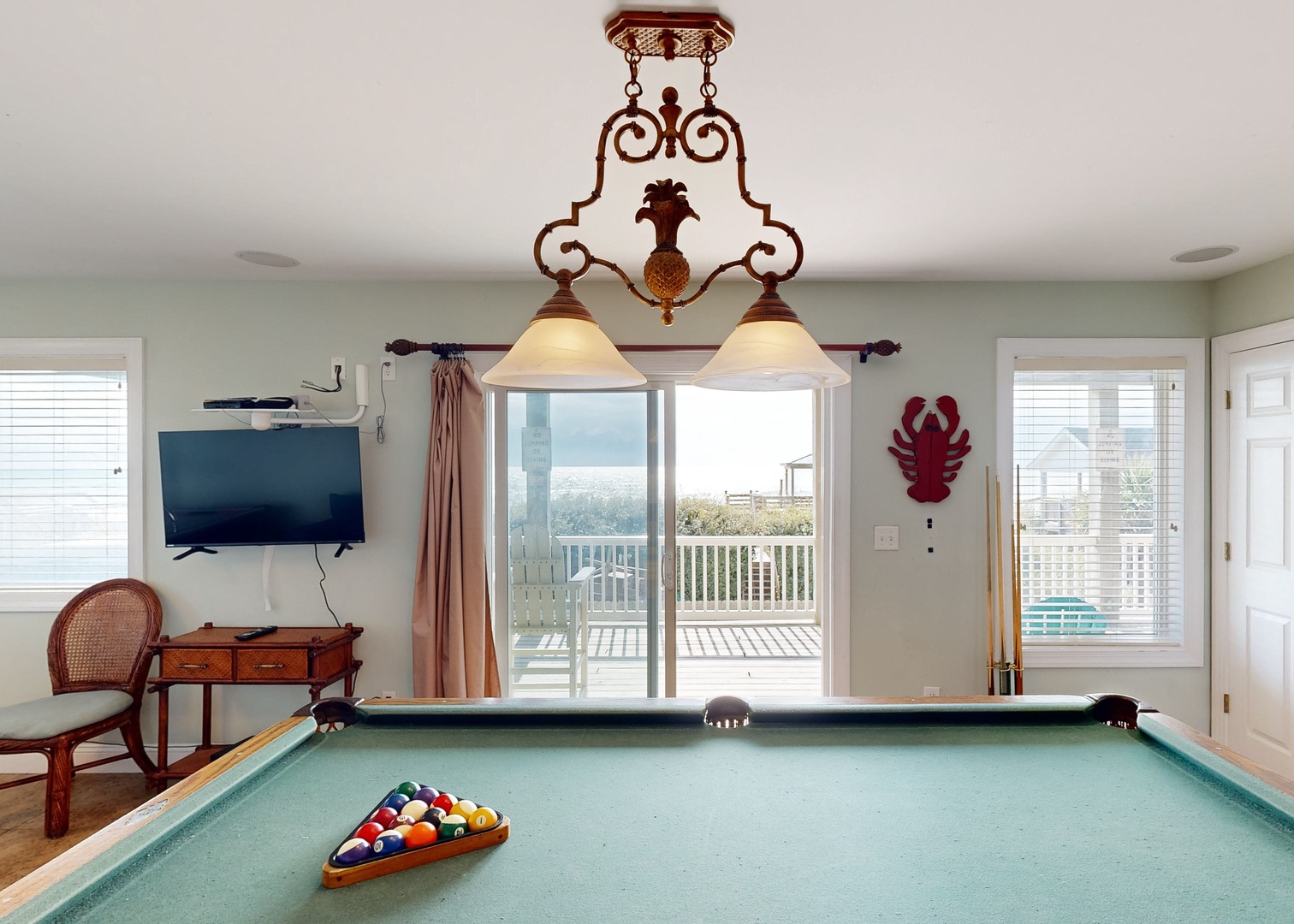 Your private game room awaits with a billiard table ready for friendly competition and a balcony beyond, opening to the coastal horizon and refreshing ocean breezes.