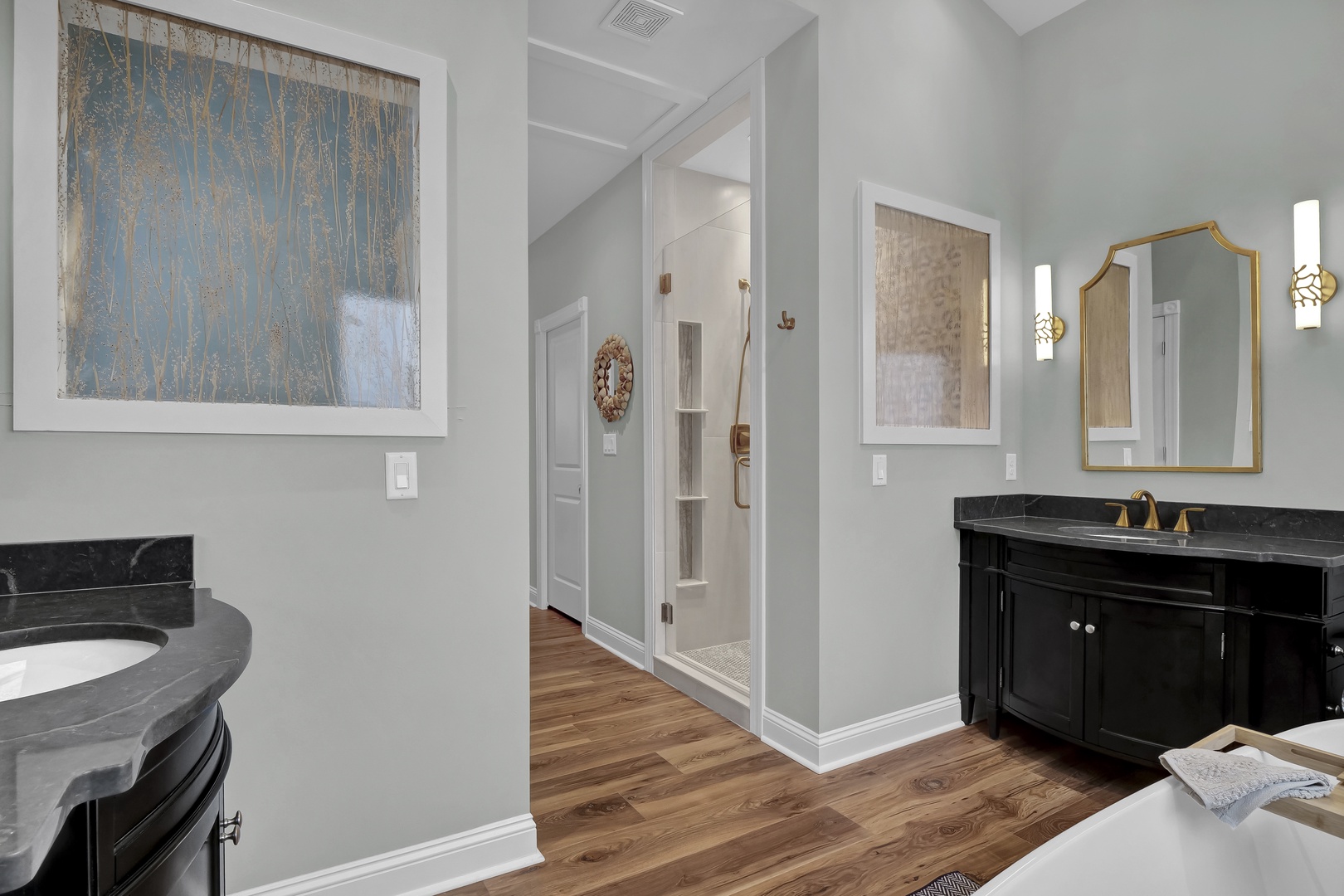 Unwind in your beautifully appointed bathroom, where elegant gold fixtures and warm hardwood floors create a spa-like sanctuary for your morning routine or evening relaxation.