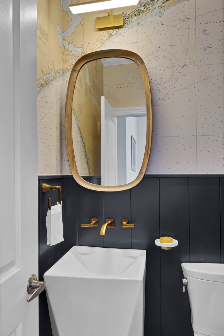 Step into a coastal-inspired sanctuary featuring sleek nautical chart wallpaper, polished brass fixtures, and modern sophistication. Your personal retreat awaits with every thoughtful detail crafted for comfort and style.
