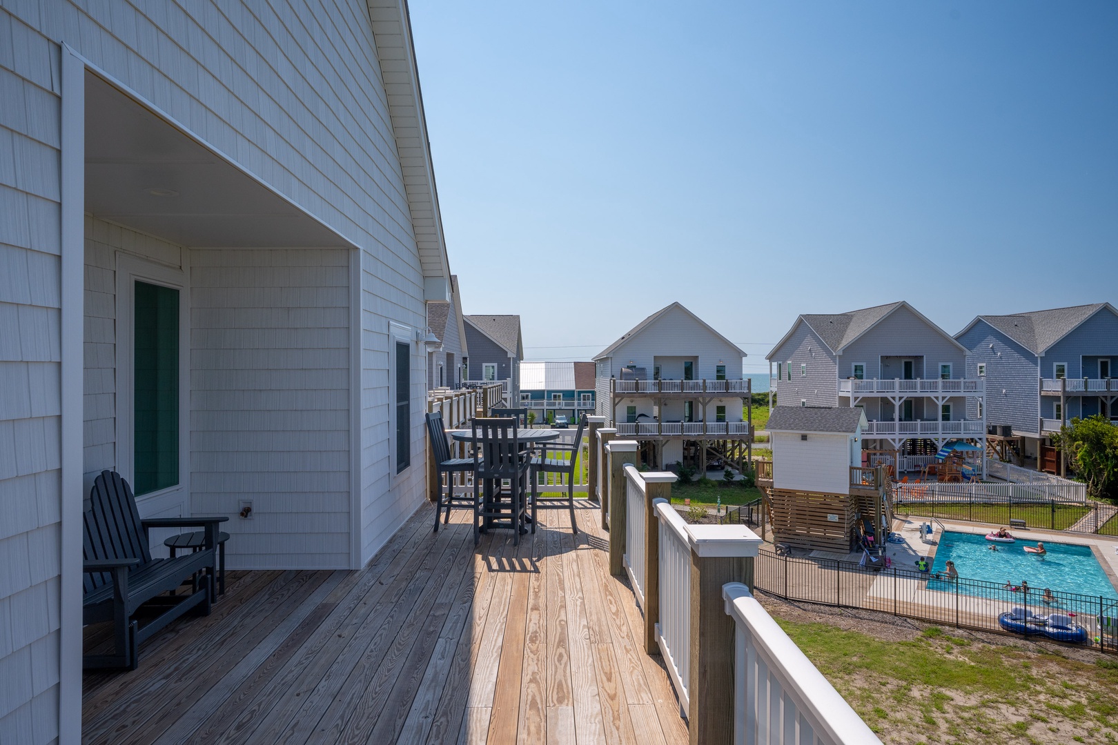 This coastal vacation rental offers quick access to the communal pool and outdoor amenities, with neighboring beach homes creating a friendly vacation community atmosphere.