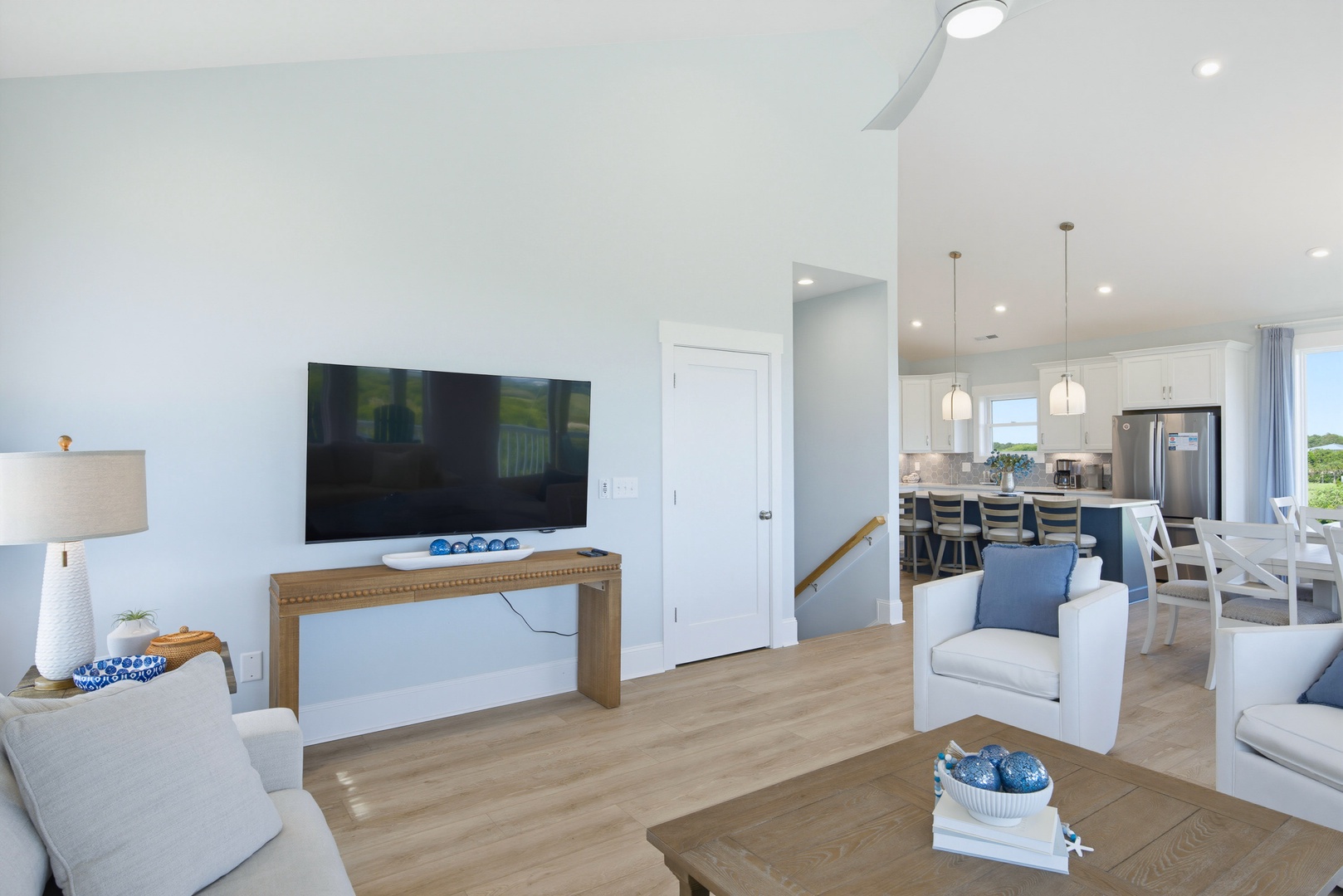 Settle into your bright, open-concept living area where soft white tones and natural light create a peaceful retreat. The open flow connects you to a fully equipped kitchen, perfect for your coastal getaway.