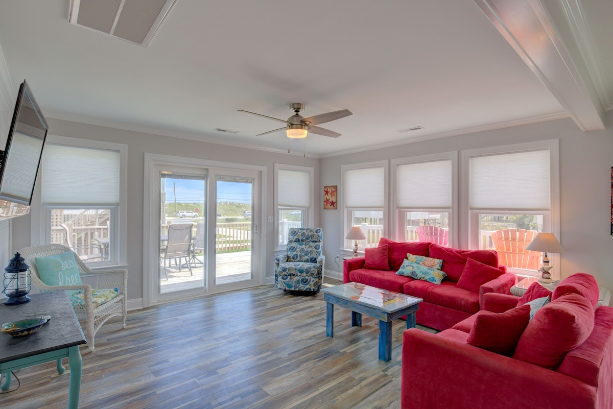 A spacious living room with a red sofa, a patterned armchair, and a coffee table.