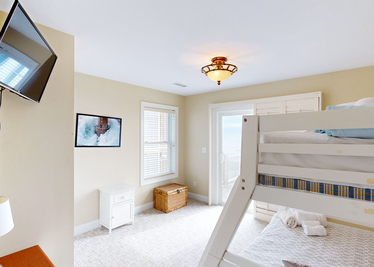 Your bright, peaceful bedroom features a bunk bed perfect for the family, with natural light streaming through windows and a glass door opening to your private balcony. Fresh towels are ready and waiting to make you feel right at home.