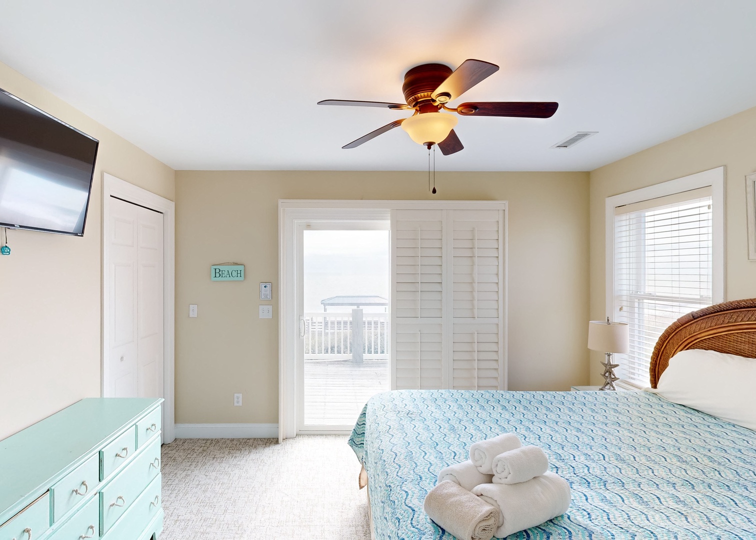 Coastal retreat with ocean breezes, cozy bed with beach linens, and ceiling fan. Every detail invites relaxation and easy coastal living.