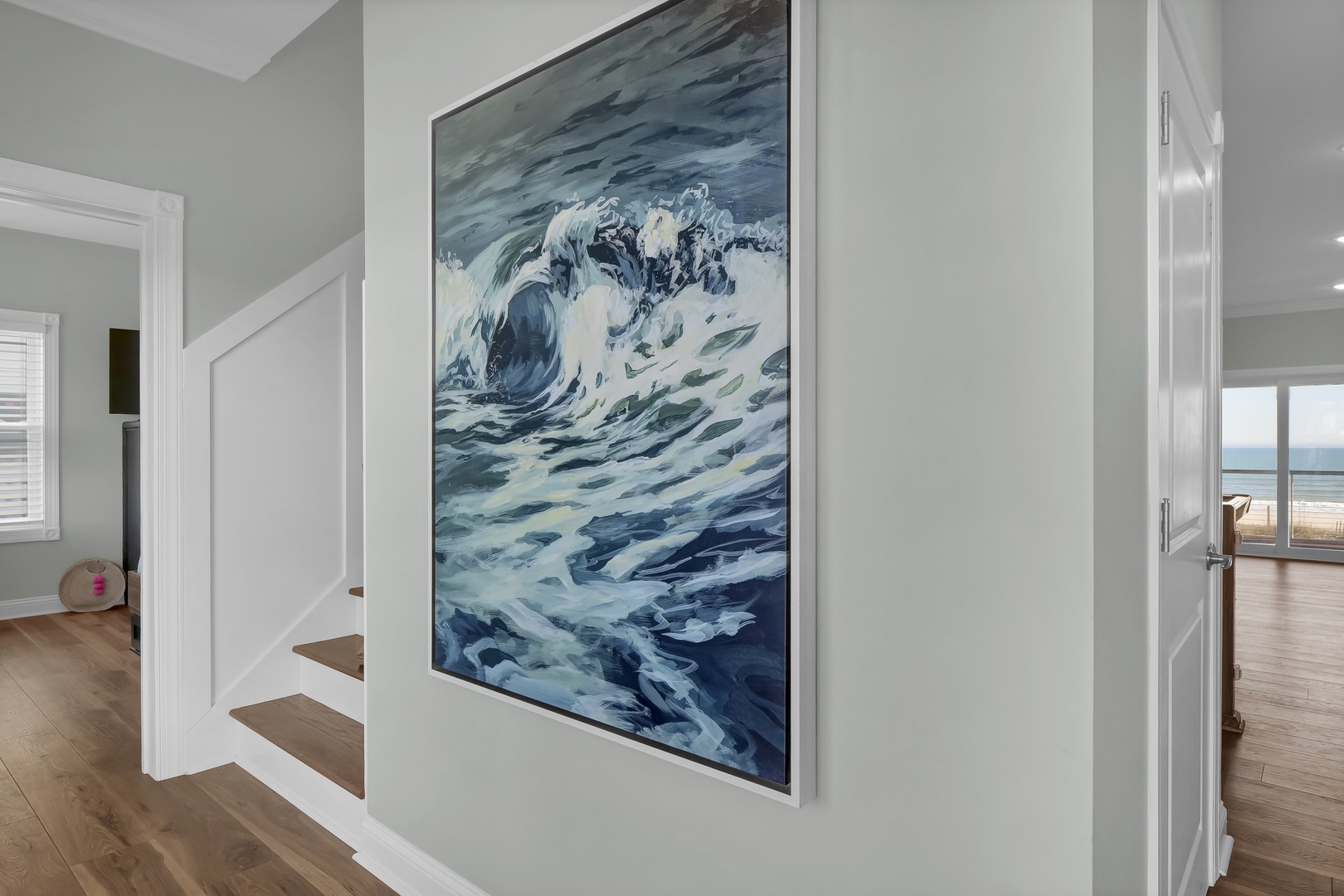A serene entryway connects the property's levels, where coastal artwork and natural light guide you toward stunning ocean views just steps away.