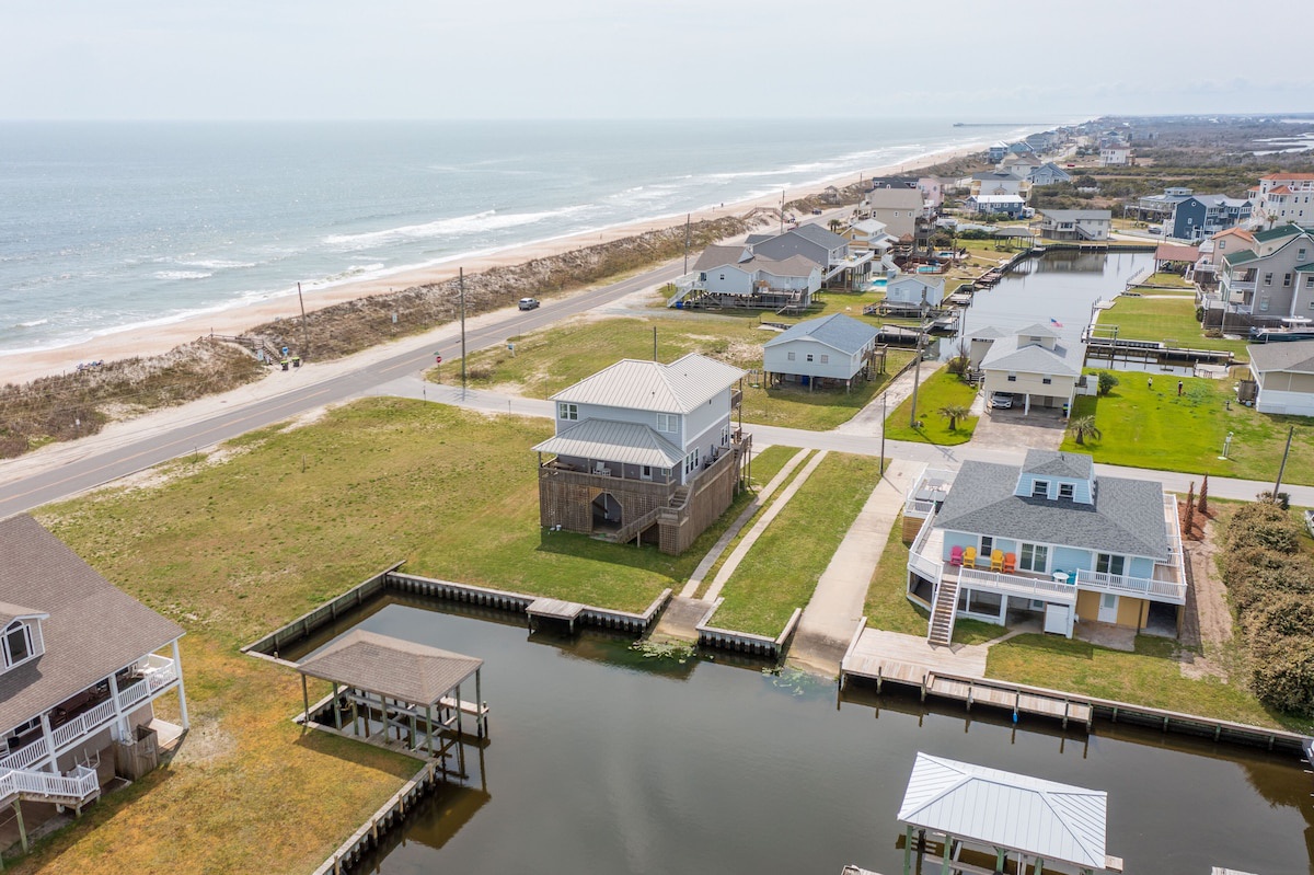 A coastal residential area with houses, a dock, and a beach.