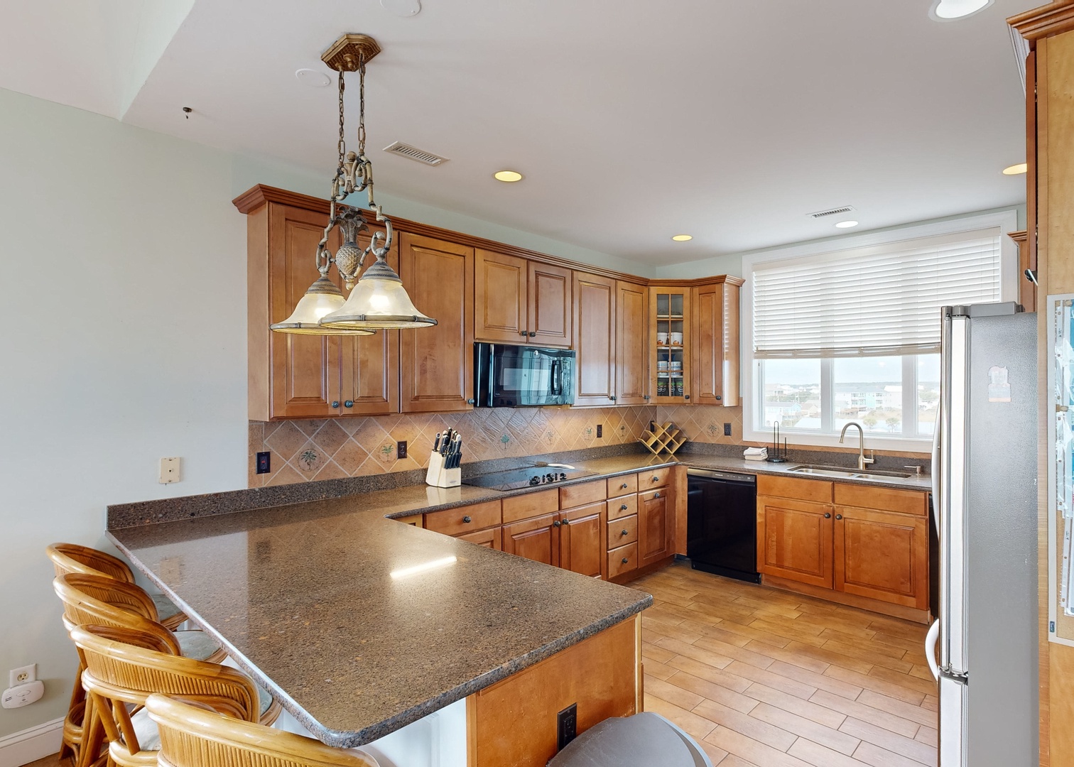 Your fully equipped kitchen features warm wood cabinetry, granite counters, and a spacious island with bar seating—perfect for preparing meals and gathering with loved ones.