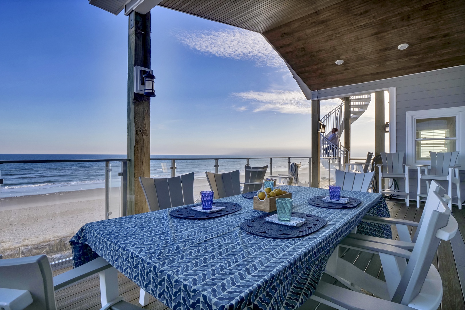 Dine steps from the waves at this oceanfront terrace, where a table set for four awaits under a covered deck with sweeping beach and sea views.
