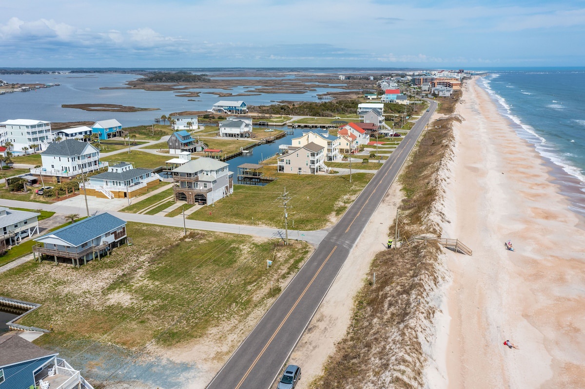 A coastal residential area with houses, a beach, and a road.