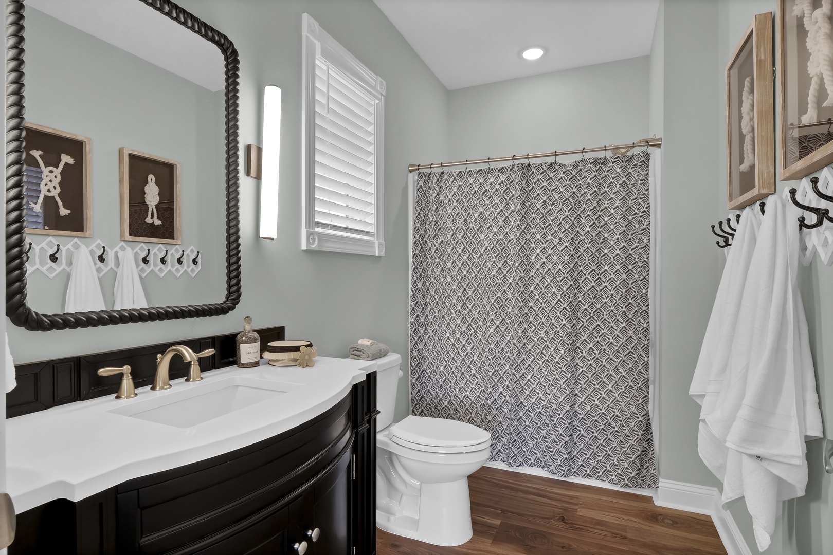 Step into a beautifully designed bathroom where coastal charm meets modern comfort. Soothing sage walls and warm wood floors create a serene retreat, while plush towels await your arrival.
