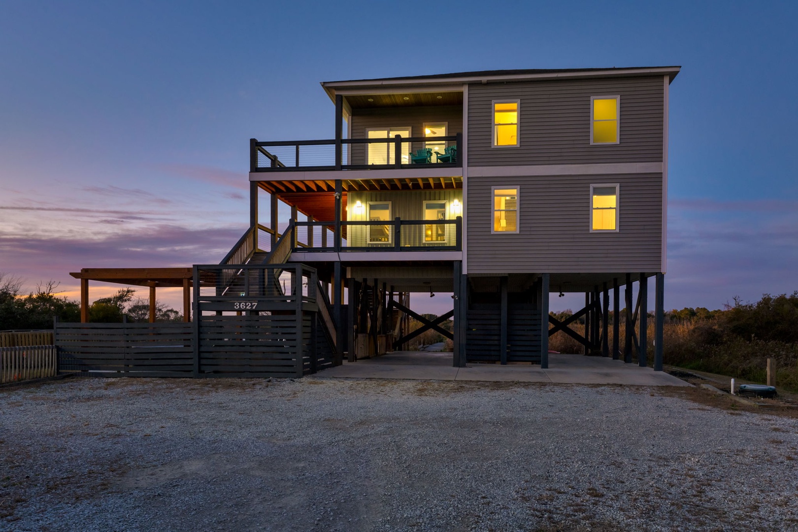 This striking elevated beach house features spacious balconies and a welcoming entrance, perfect for coastal living and enjoying the sunset views from your private outdoor spaces.