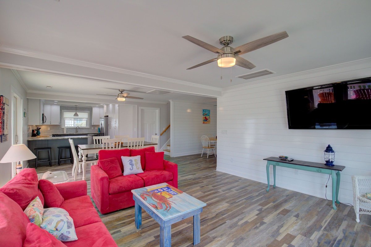 A spacious living room with a red sofa, a small table, and a ceiling fan.