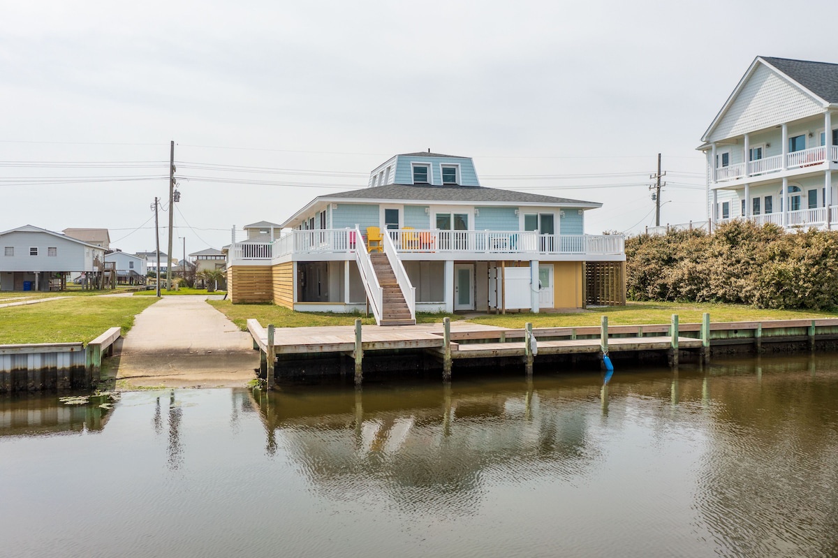 A waterfront property with a dock, a staircase leading to a balcony, and a view of the water.