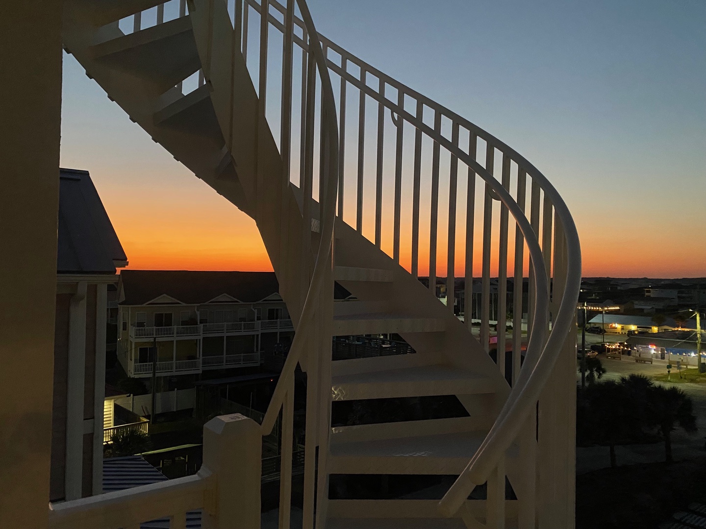 A stunning sunset paints the sky in warm hues as evening settles over this coastal neighborhood, framing the staircase that leads to your elevated retreat.