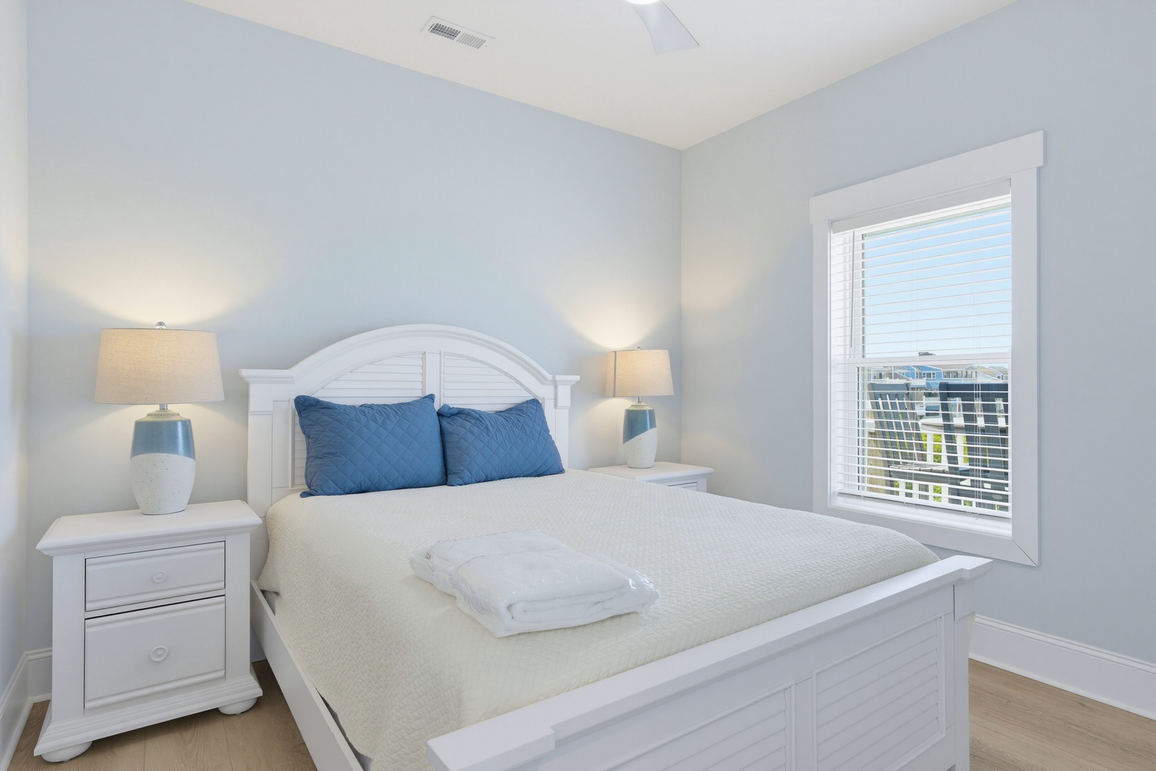 Slip into your peaceful retreat with crisp white linens and coastal blue accents. Natural light pours in through the window, creating a serene space where you can unwind completely.