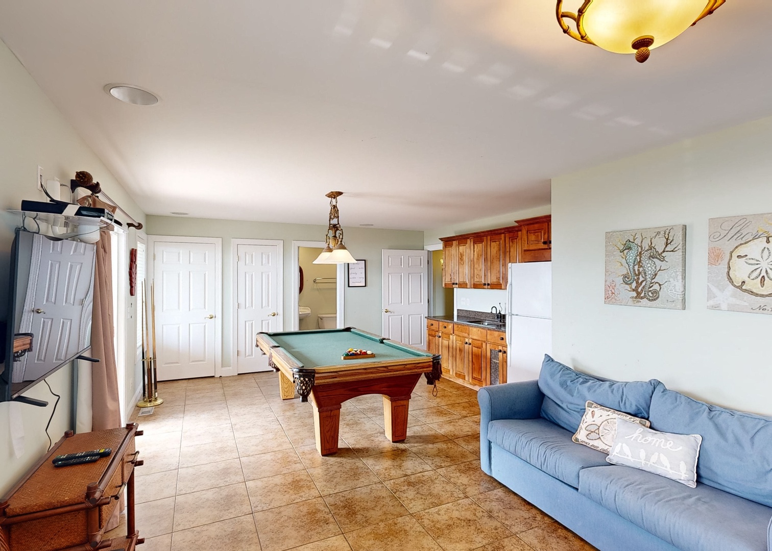 Your vacation retreat features a versatile entertainment space where you can challenge friends to billiards, unwind on the cozy sofa, and whip up snacks in your own kitchenette—all in one inviting room.