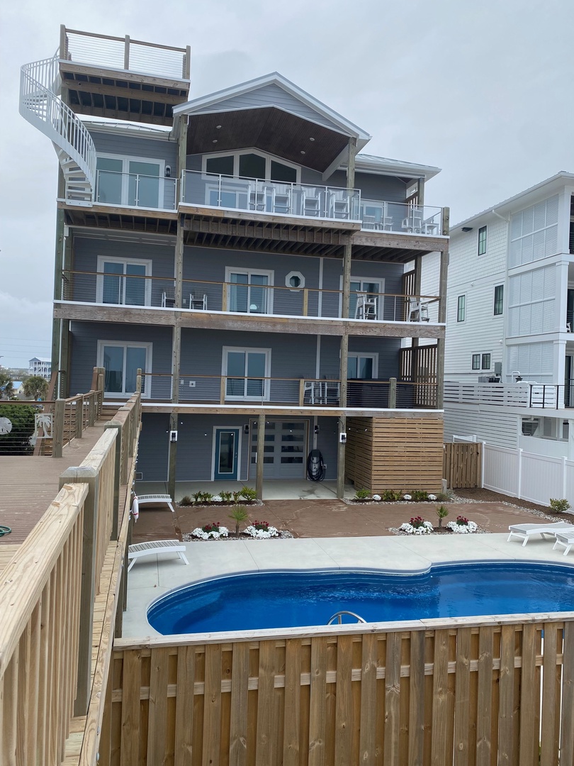 Modern multi-story property with private balconies, poolside decking, and landscaped grounds just moments from the beach.