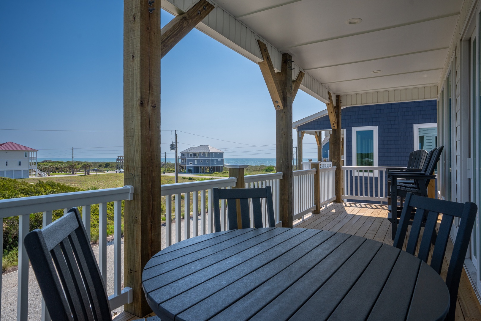 Step onto your private covered porch with coastal views and enjoy morning coffee or evening relaxation in the fresh sea breeze. The comfortable seating invites you to unwind while taking in glimpses of the nearby beach.