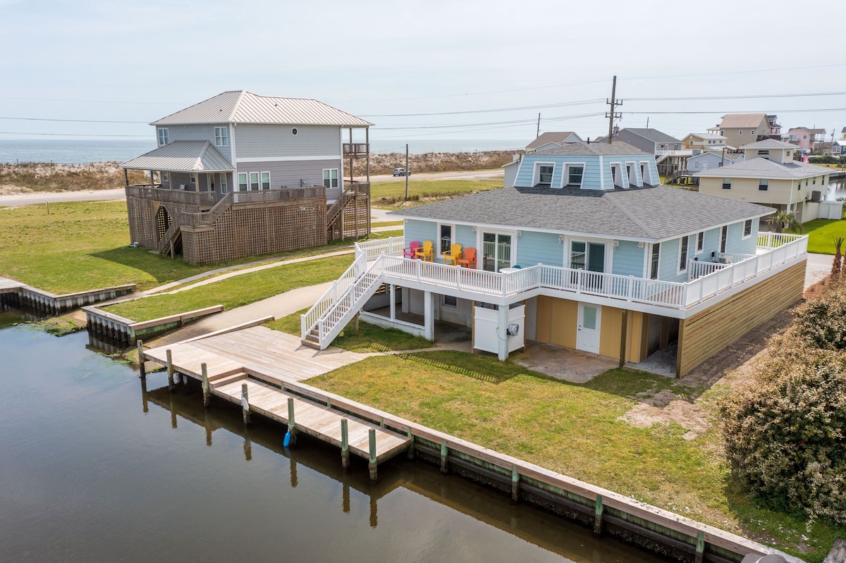 A waterfront property with a dock, a covered deck, and a two-story house with a balcony.