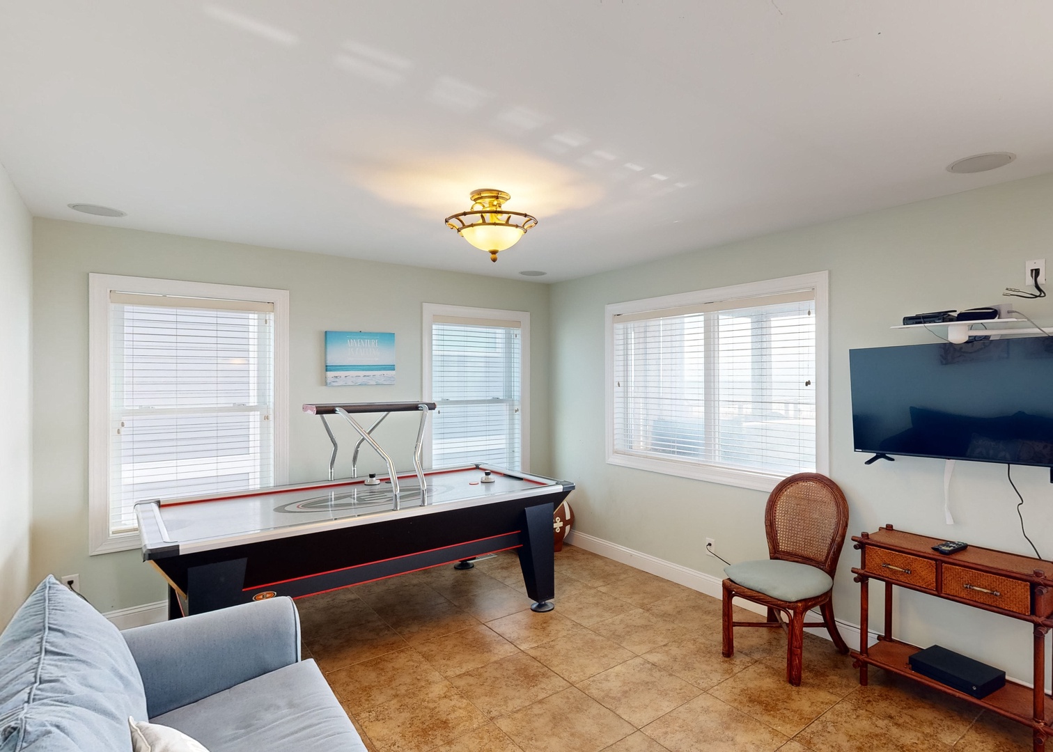 Challenge your friends to air hockey or relax on the sofa in this bright entertainment room. Large windows fill the space with natural light, making it perfect for game days and downtime.