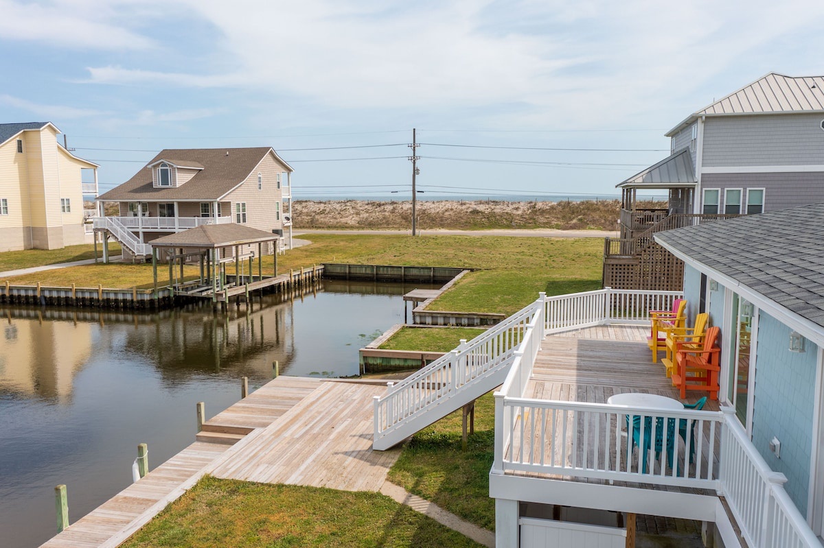 A waterfront property with a dock, a covered deck, and a view of the water.