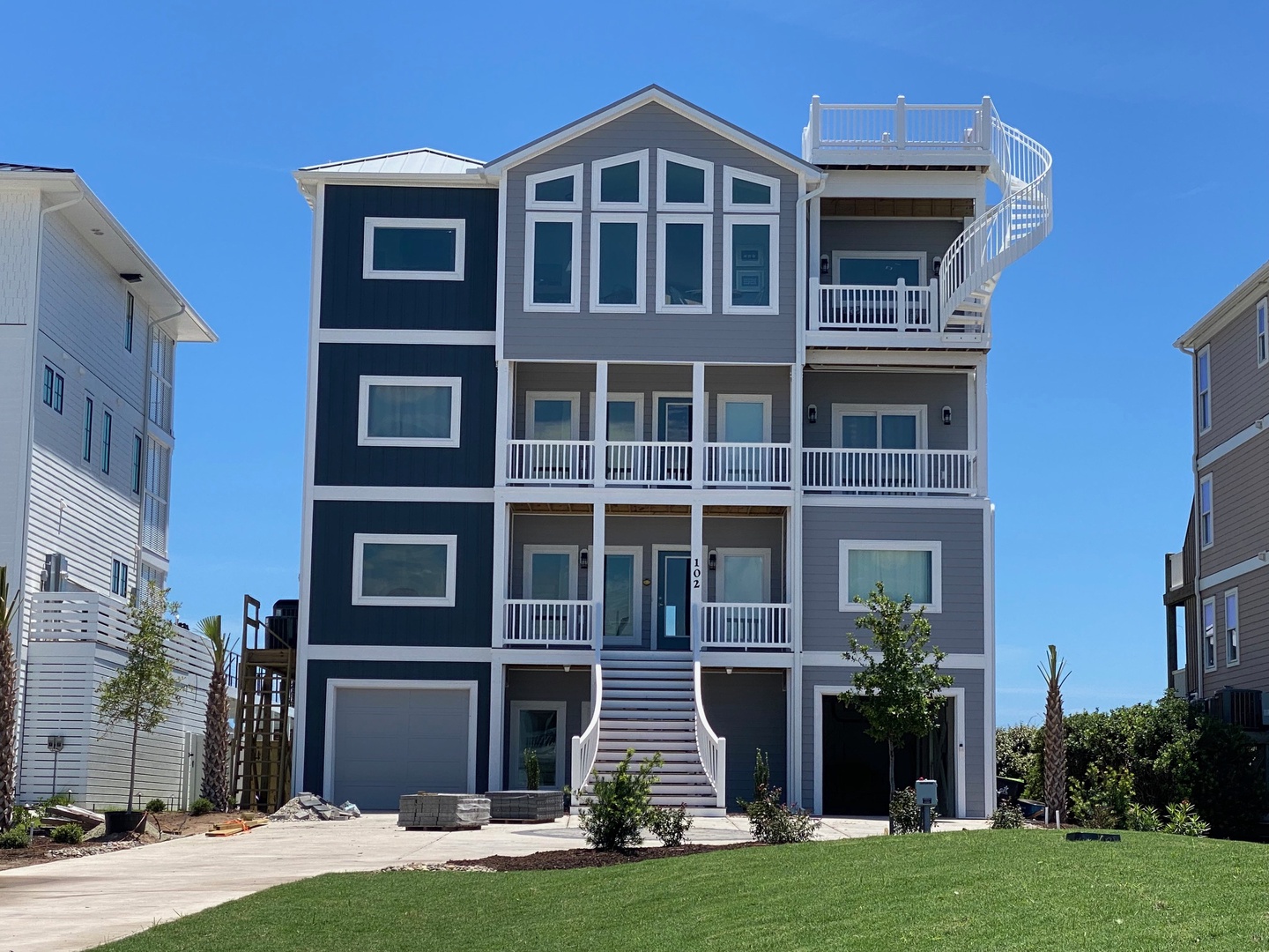 This stunning four-story coastal property features bright white trim against charcoal siding and multiple private balconies. The rooftop deck and elevated design promise ocean breezes and memorable sunsets nearby.