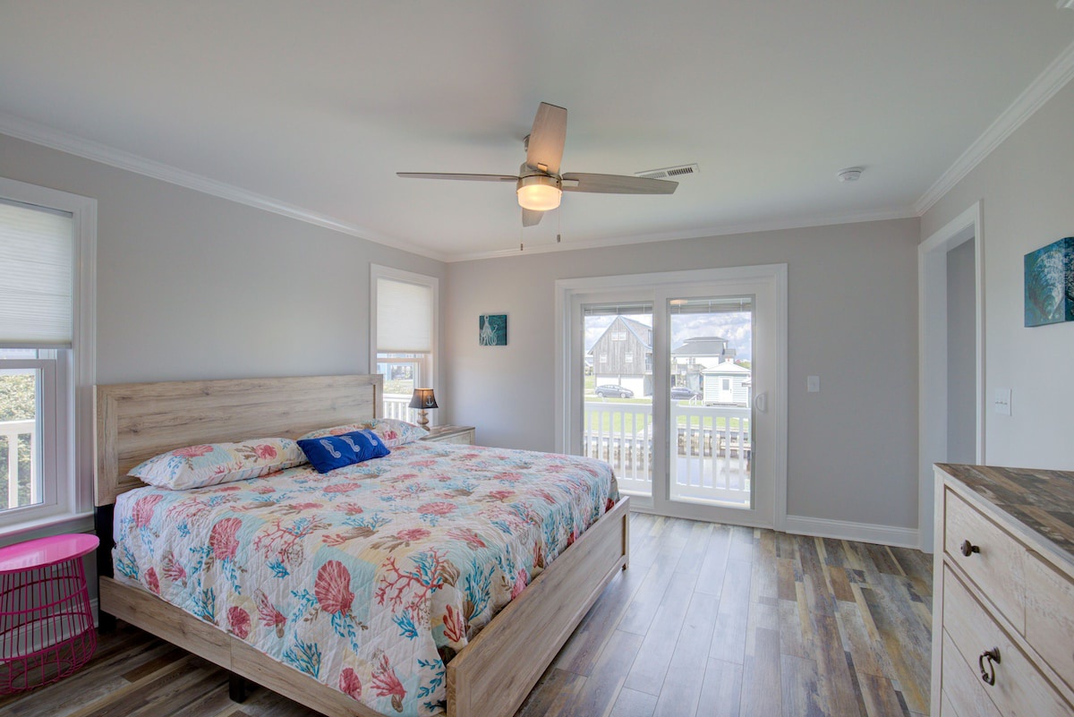A bedroom with a wooden bed, a ceiling fan, and a view of the outside through a sliding glass door.