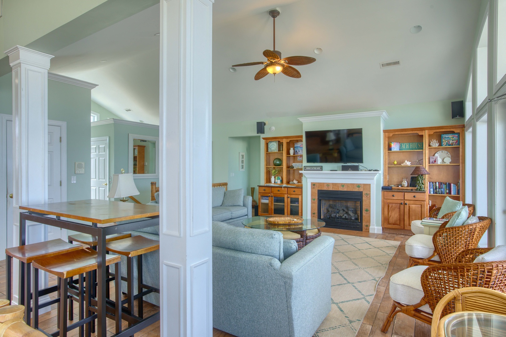 Relax in this open coastal-inspired living room with a cozy fireplace, ample seating, and high ceilings that invite natural light—perfect for unwinding after a day of exploring.