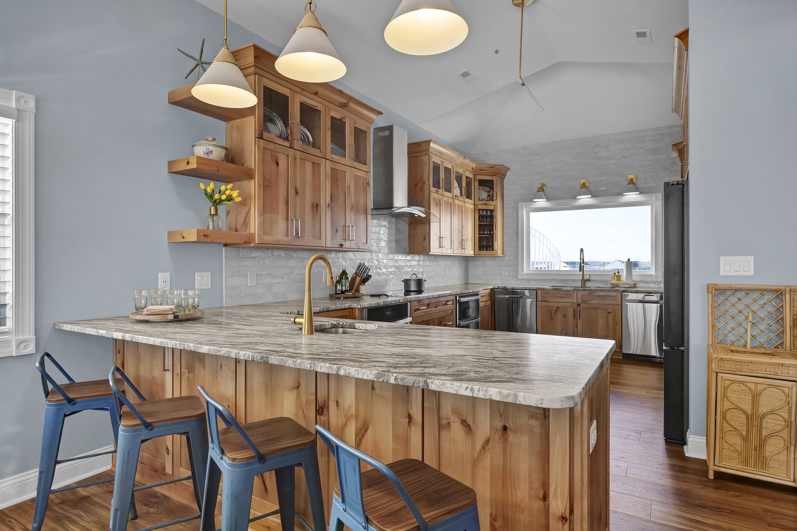 Gather around the spacious kitchen island with gleaming granite countertops and rustic wood cabinetry. Natural light pours in as you prepare meals with modern appliances and enjoy the open, airy design—perfect for your vacation retreat.
