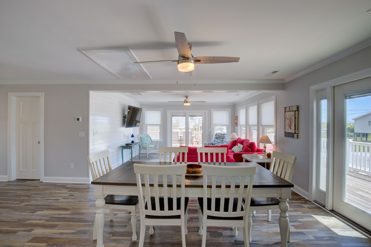 A dining area with a wooden table, white chairs, and a ceiling fan.