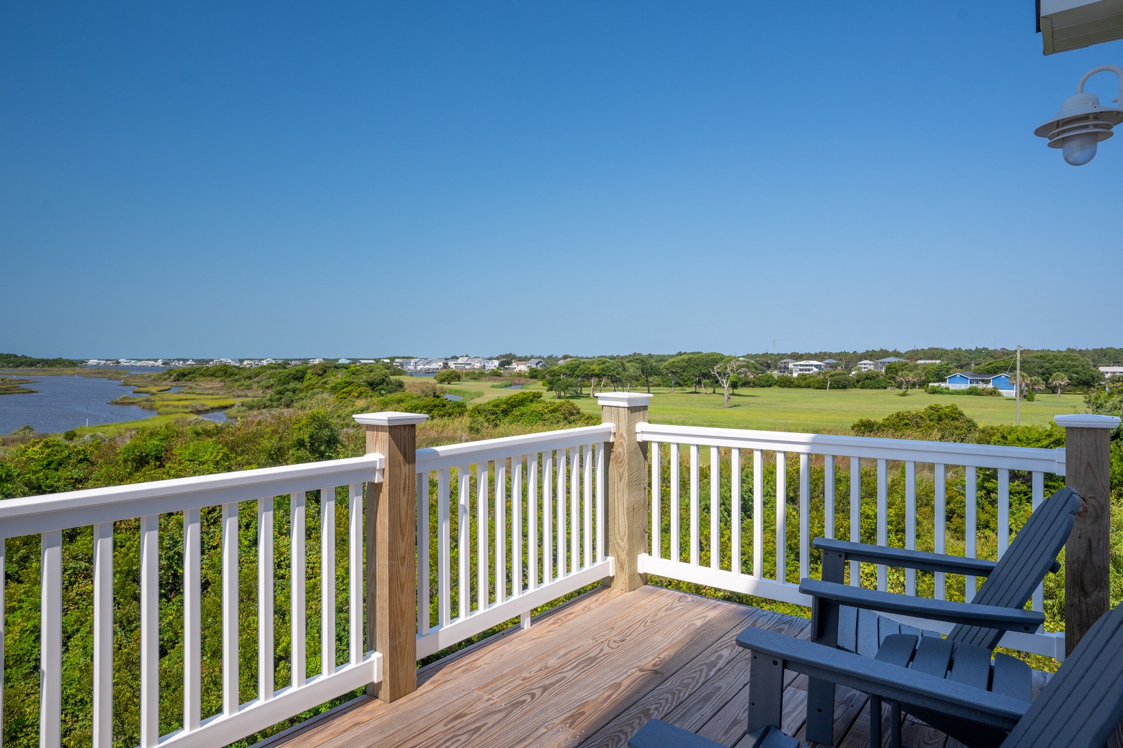 A coastal retreat where lush marshland meets open sky, perfect for quiet mornings on your private deck overlooking the serene waterway and verdant landscape.