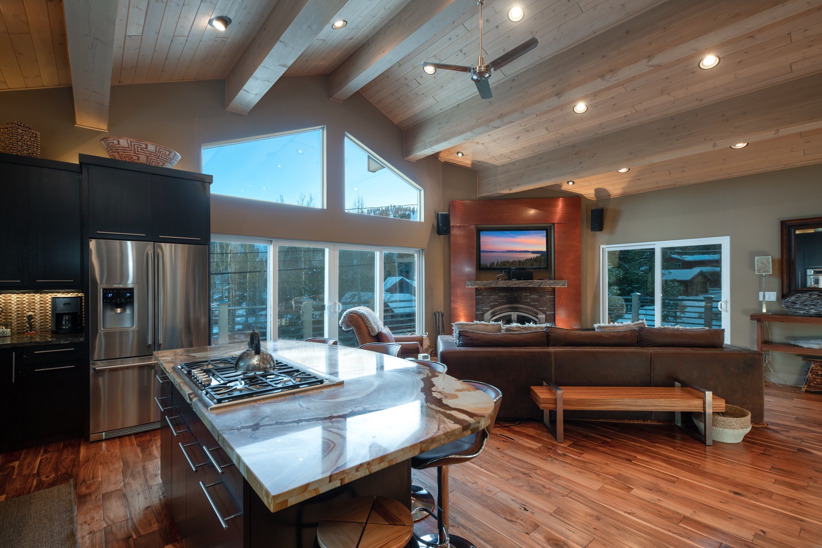View over kitchen island of living room with fireplace and wall mounted tv: Eagle's Nest Lodge