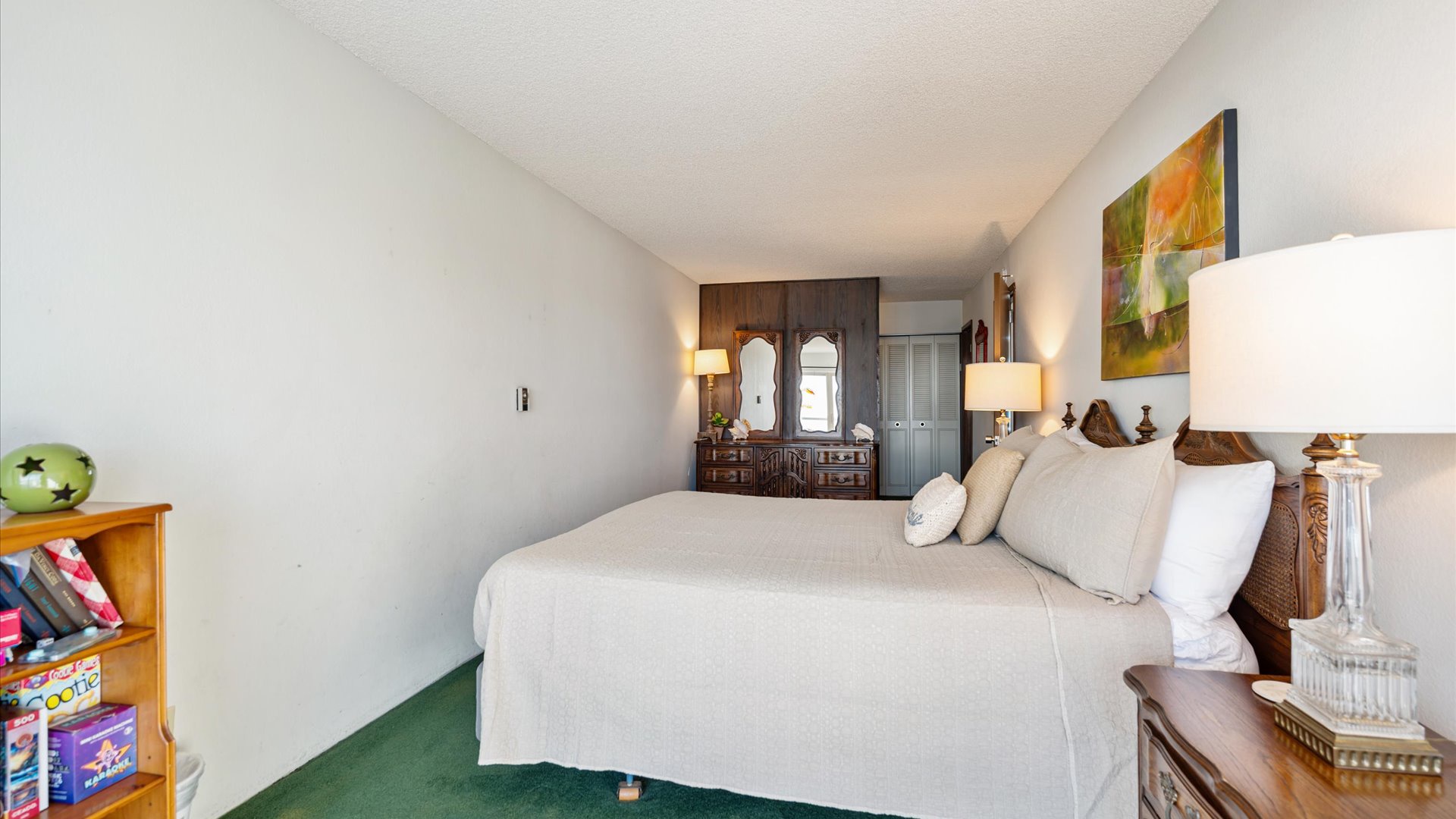 Charming primary bedroom with vintage wooden furnishings, ornate mirrors, and cozy seating for a warm, homey atmosphere