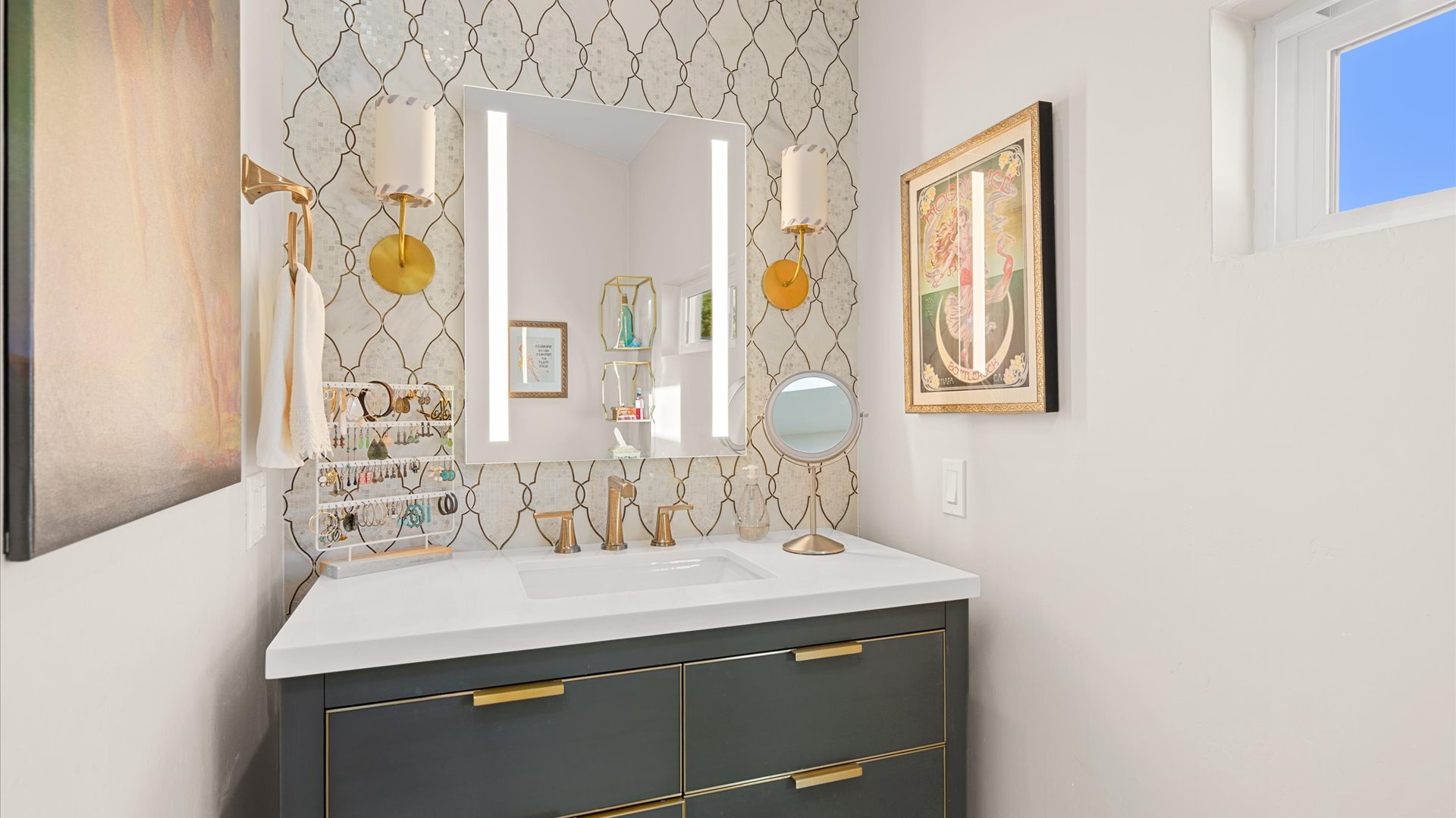 Master bathroom featuring golden patterned wallpaper, modern vanity, and warm brass accents