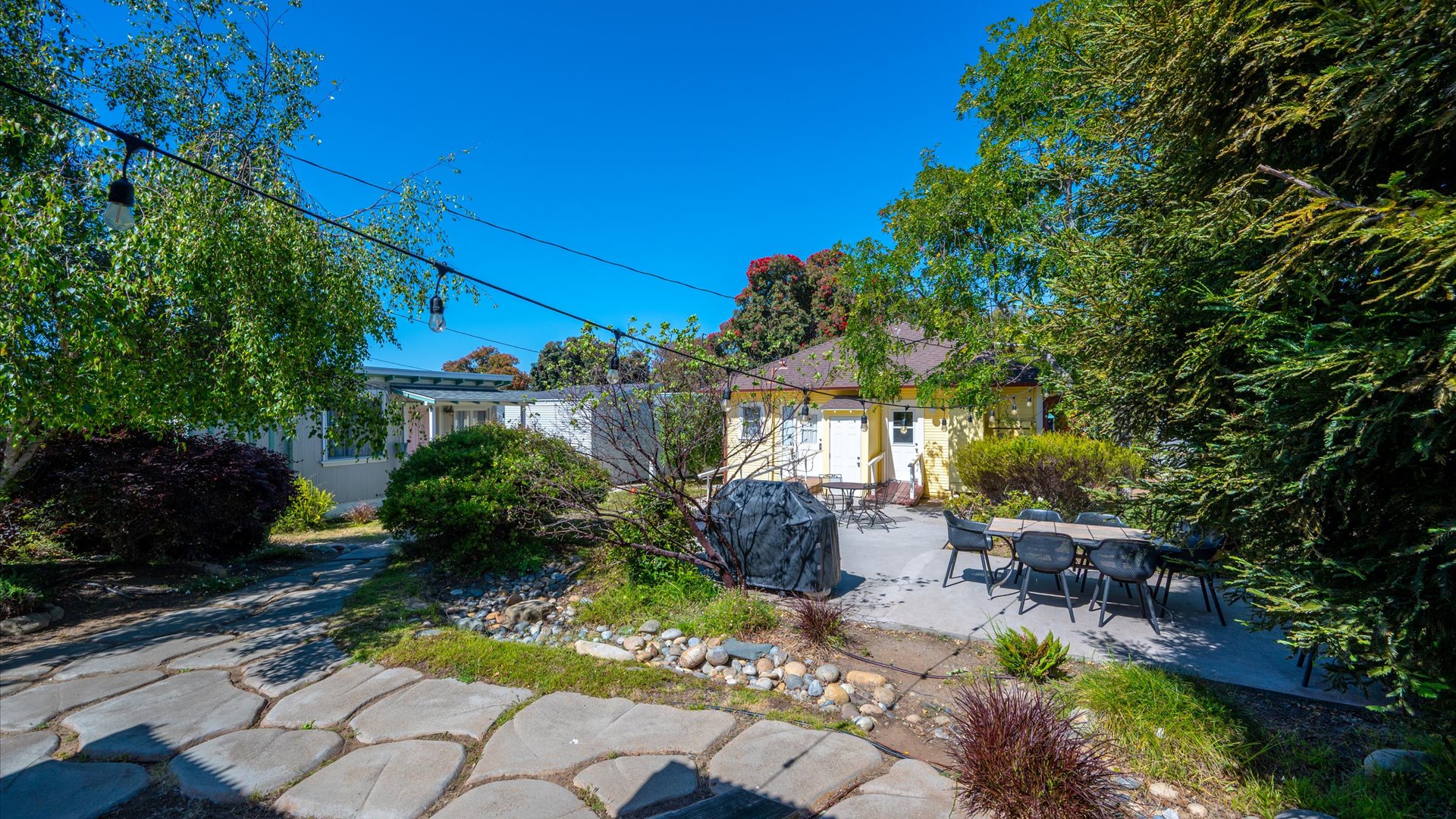 The beautifully landscaped backyard is a peaceful retreat complete with fire pit. dining area, and ample space to relax