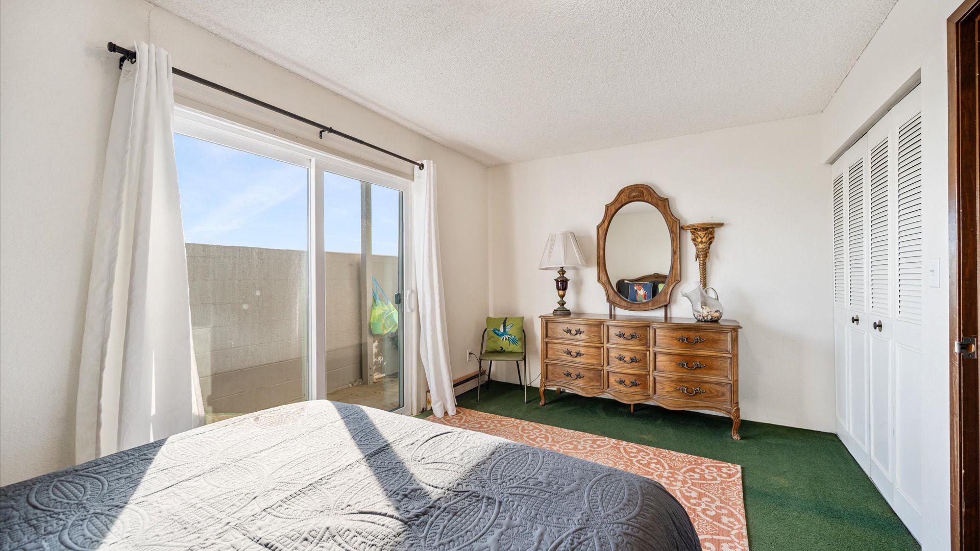 wake up to sounds of waves in this bright bedroom featuring vintage charm with ornate wooden furniture