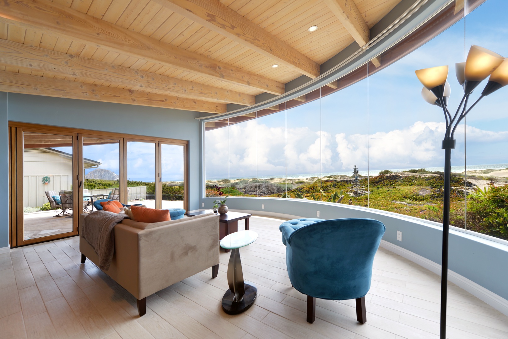 Sink into plush seating and let natural light flood this airy retreat, where floor-to-ceiling windows frame sweeping coastal dunes and endless sky—your private sanctuary between land and sea.