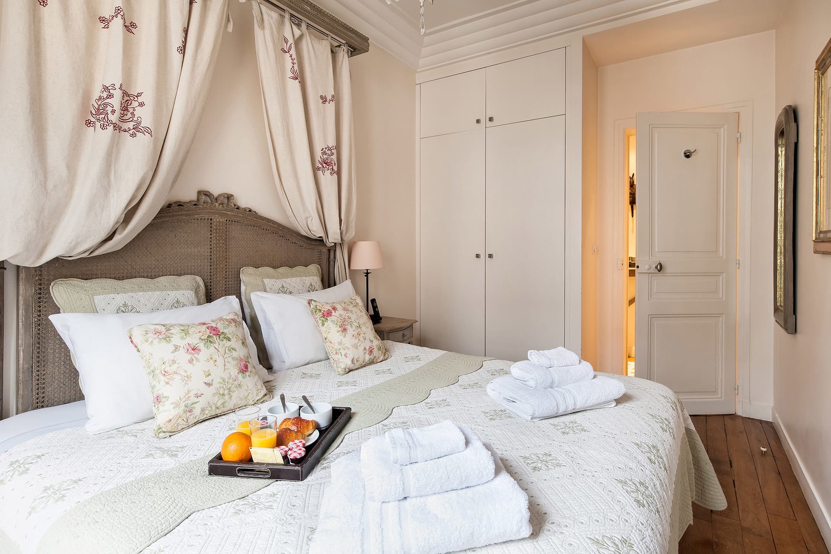 The bedroom features an antique headboard and chandelier.